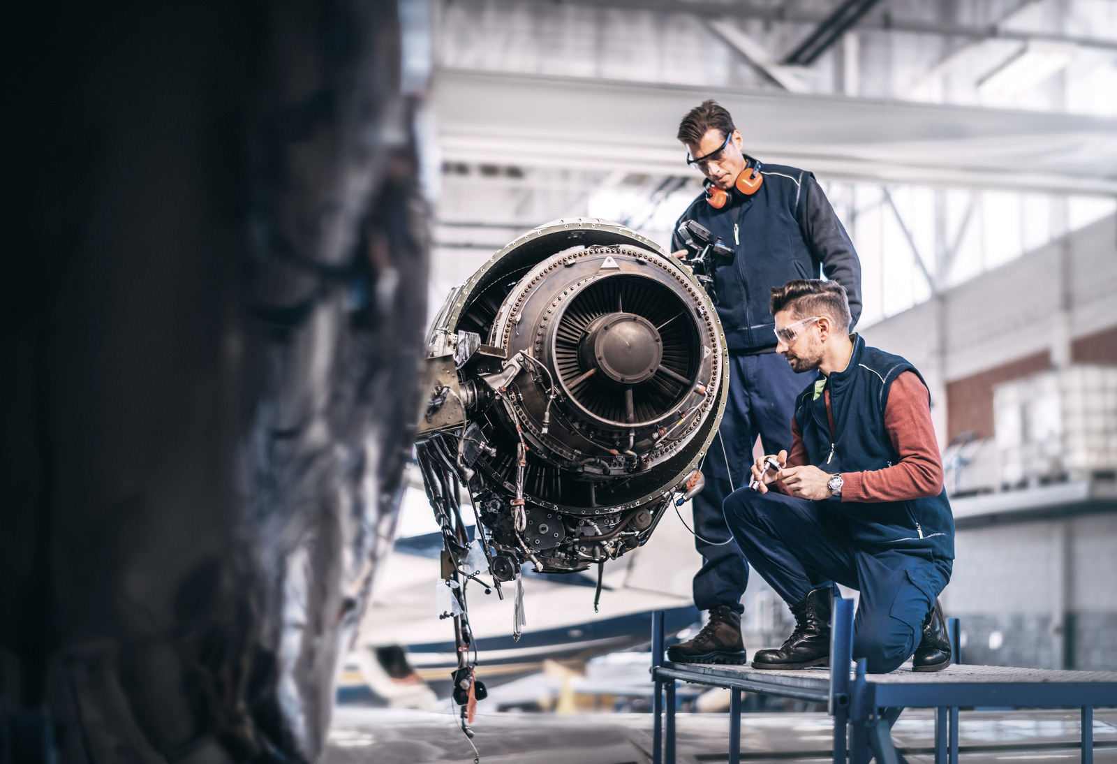 Engineers working on a partially disassembled jet engine